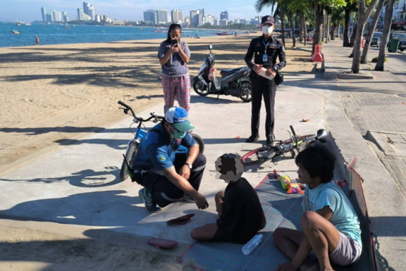 Официальные лица разговаривают с 10-летним беспризорником на пляже. О втором ребенке на фото ничего неизвестно. Chaiyot Pupattanapong